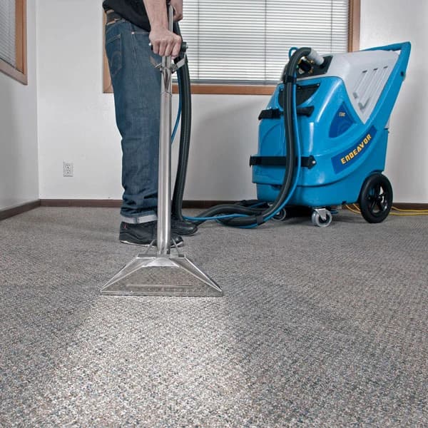Person using a professional blue carpet extractor and metal wand on a grey speckled carpet.
